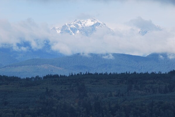 Une chaîne de montagnes dont le sommet enneigé est partiellement dissimulé par les nuages.