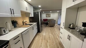 Una cocina moderna con armarios blancos, un refrigerador de acero inoxidable y una encimera de madera.