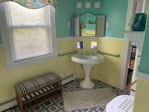 A bathroom with a sink, window with blinds, bench, patterned floor, and a toilet. - Cozy 1-bedroom apartment in charming Sanford within 20 minutes to Maine beaches (Sanford)