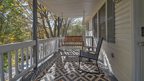 A covered porch with a patterned floor, a rocking chair, and a bench. - Charming 3-bedroom cottage  (Abingdon)