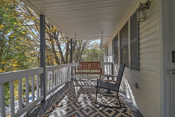 A covered porch with a patterned floor, a rocking chair, and a bench. - Charming 3-bedroom cottage  (Abingdon)