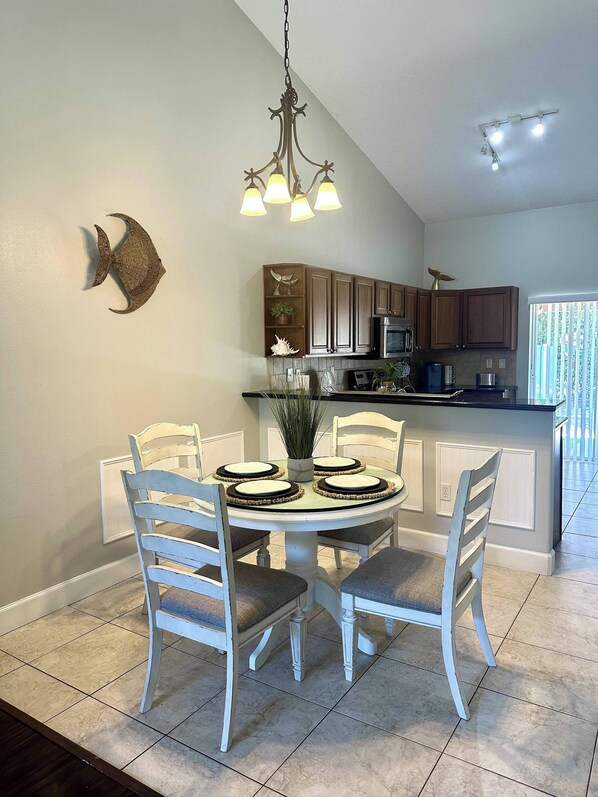 Un coin repas comprenant une table ronde, six chaises et un lustre.