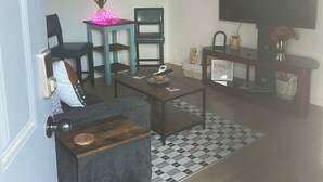 Un soggiorno con ventilatore a soffitto, televisore, tavolino, divano e tappeto decorato.