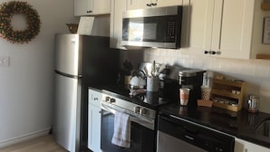 Una cucina moderna con elettrodomestici in acciaio inossidabile, mobili bianchi e un'elegante ghirlanda decorativa appesa al muro.