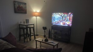 Un soggiorno con televisore, lampada, tavolo e divano.