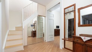 A hallway with wooden flooring, a staircase, a mirror, and a wooden cabinet. - Maya Home (Sorrento)