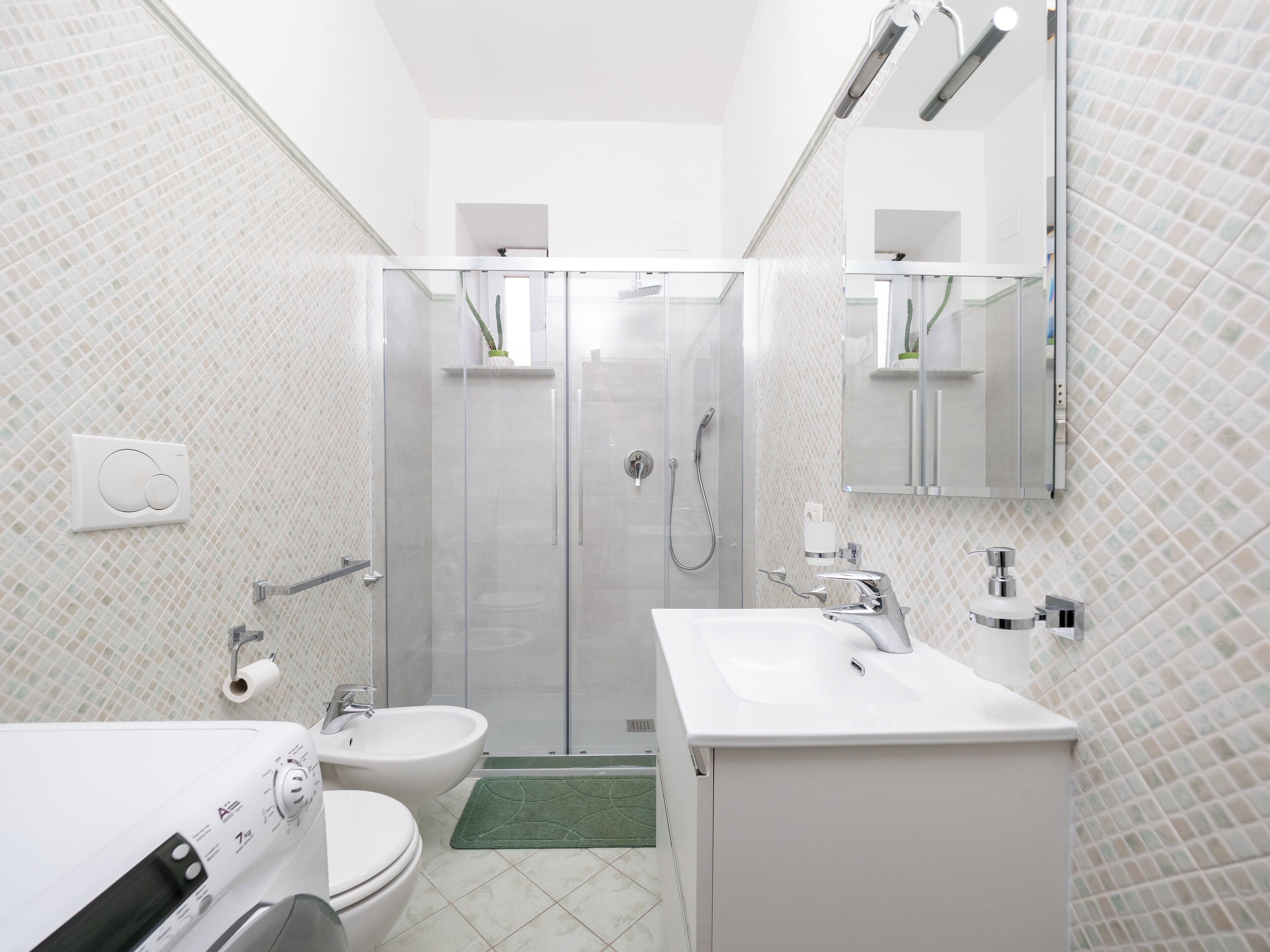 Uma casa de banho moderna com chuveiro de cabine de vidro, lavatório branco e sanita.
