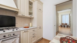 A kitchen with a stove, oven, and cabinets. There is a dining table with chairs and a basket. - Maya Home (Sorrento)