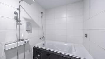 A modern bathroom with a bathtub, a shower area, and a toilet.