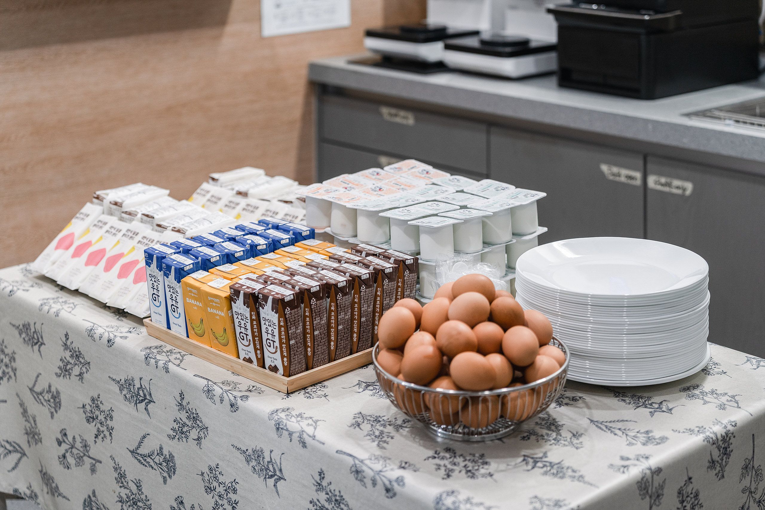 A breakfast buffet with various food items and a stack of white plates.