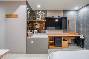 A modern hotel room with a large flat-screen TV, wooden furniture, and a tiled wall. - The Ciel Hotel (Gyeongju)
