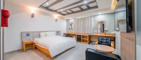 Una habitación de hotel con cama, mesitas de noche, un escritorio con silla, un espejo y televisión.