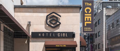 Entrada de un hotel con un letrero que dice 'Hotel The Ciel' y un letrero de 'Registro Salida'.
