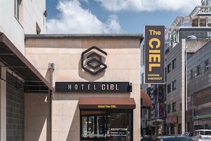 Entrada de un hotel con un letrero que dice 'Hotel The Ciel' y un letrero de 'Registro Salida'.