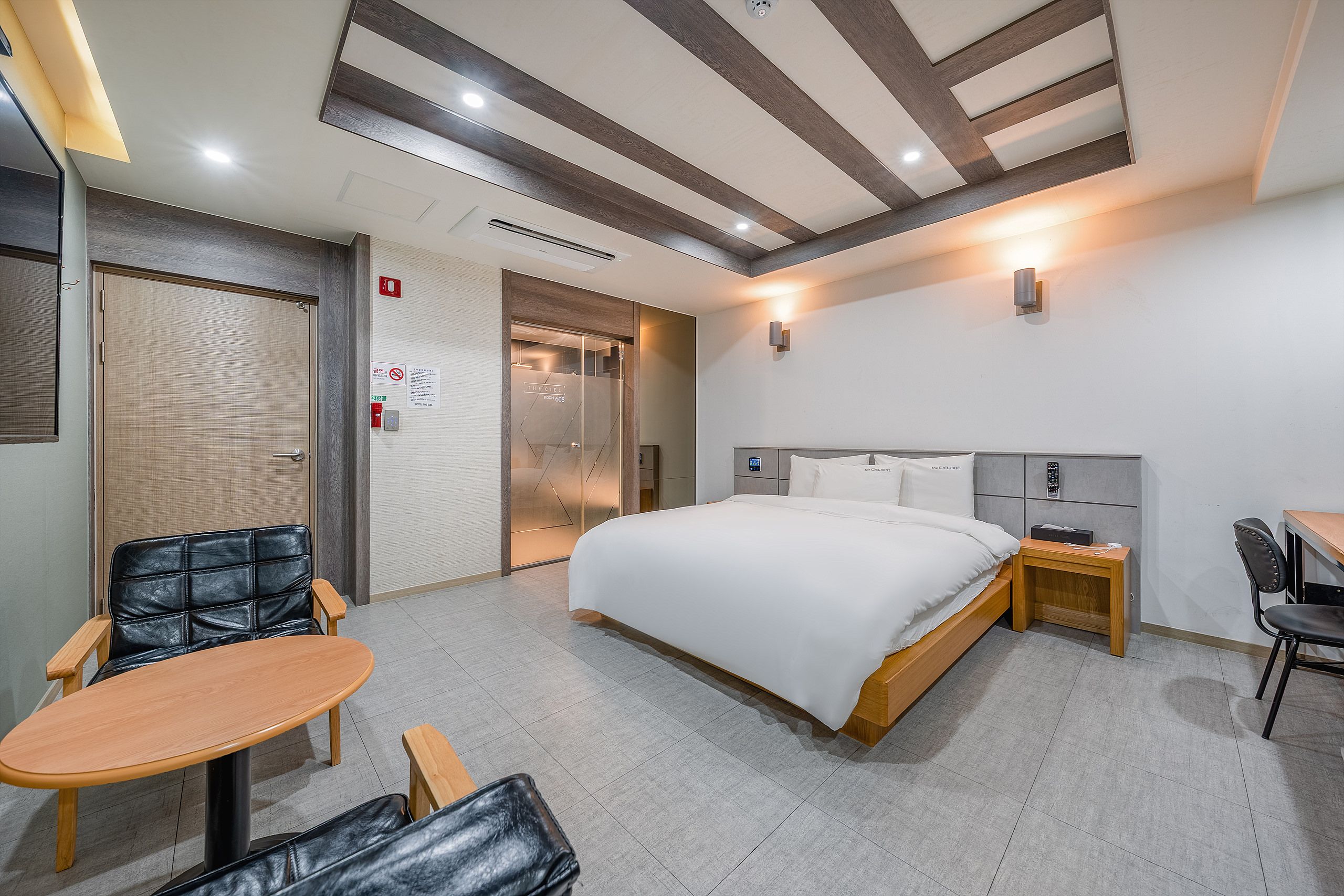 A hotel room with a bed, a desk, a chair, and a small table.