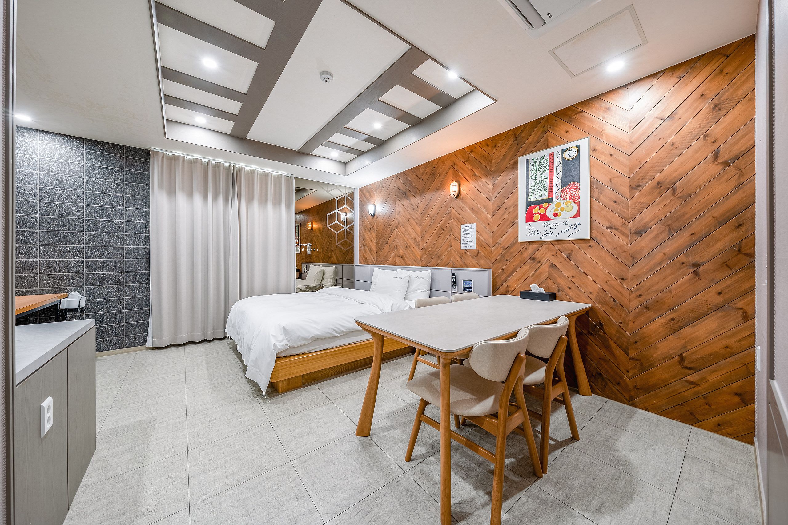 Ein modernes Schlafzimmer mit einem Bett, einem Nachttisch und einer Wand mit Holz-Fischgrätmuster.