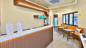 A reception area with a wooden reception desk, a digital sign, and seating with a view.