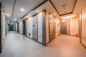 A hotel corridor with multiple doors, each marked with a number, and a fire extinguisher on the right.