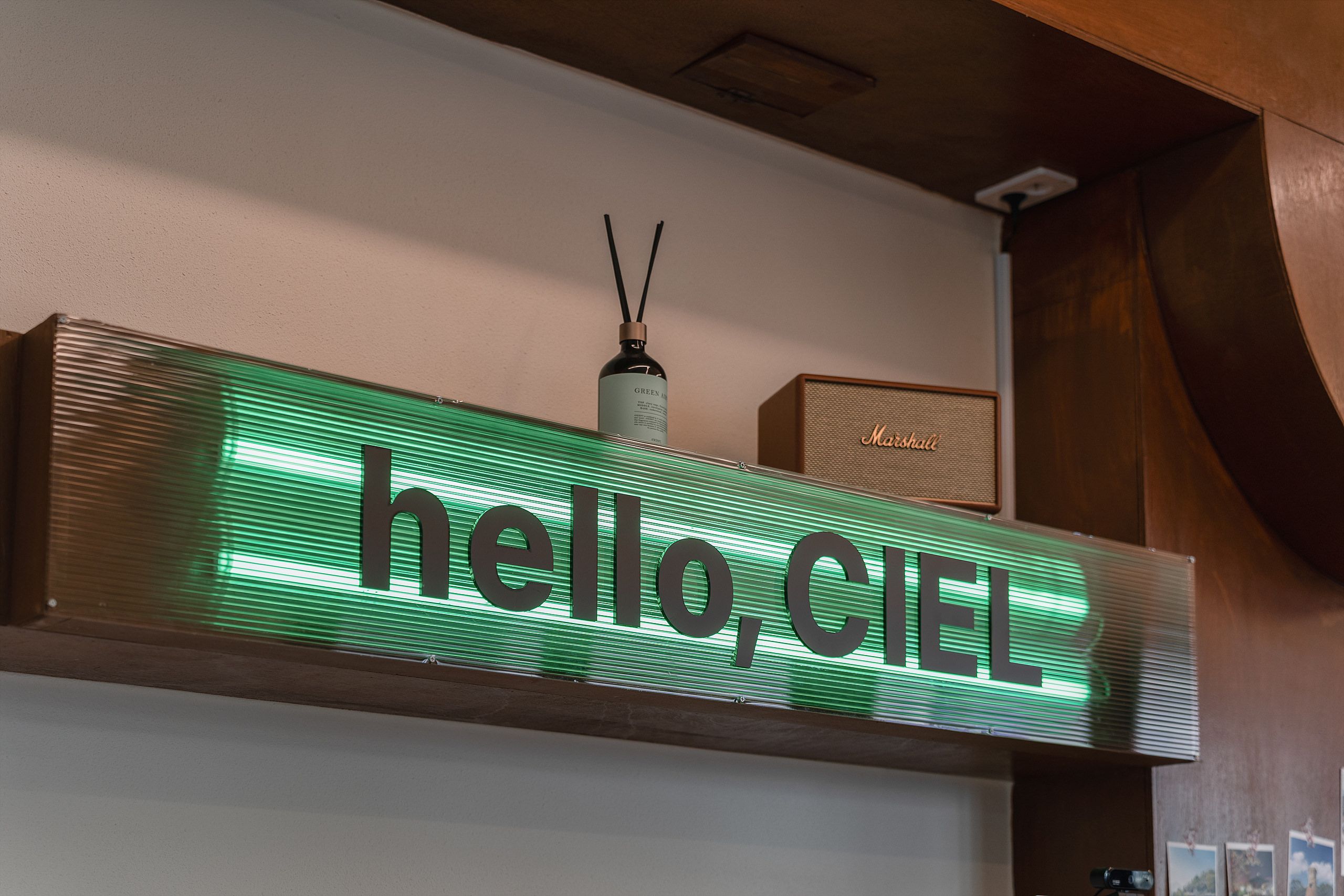 A green illuminated sign with the words 'hello, CIEL' on a wall.