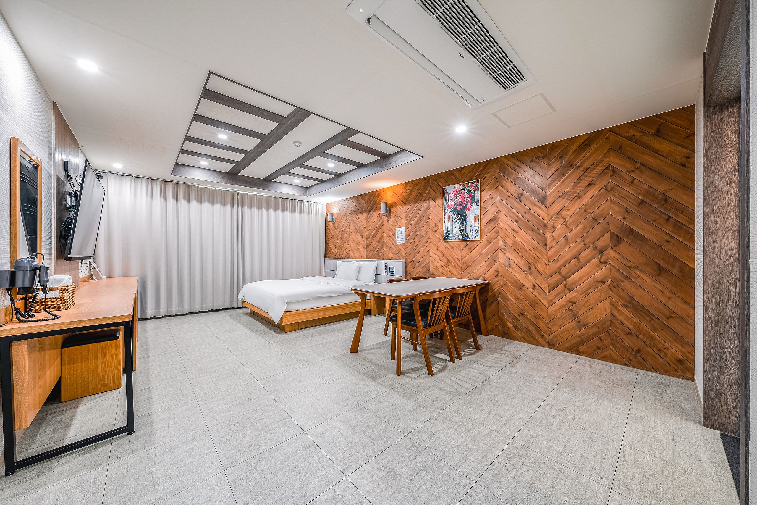 Una habitación de hotel moderna con una cama, un escritorio y una mesa de comedor.