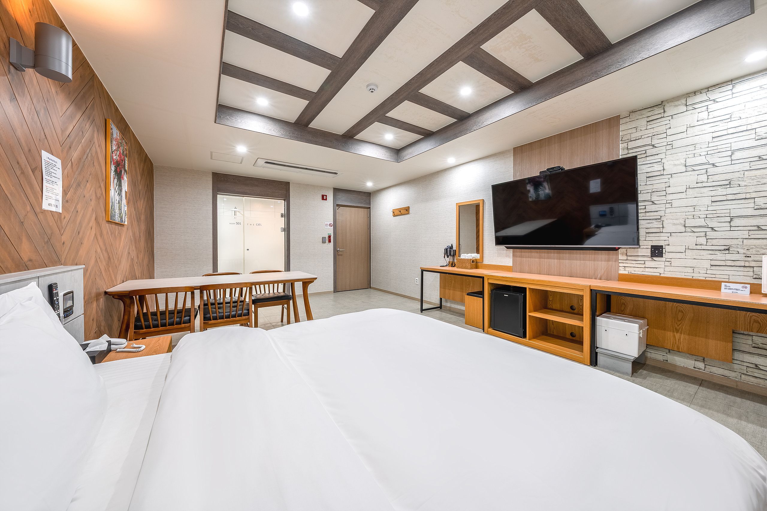 A hotel room with a bed, a desk, a television, and a bathroom.