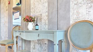 A room with a light blue console table, a white vase with flowers, a mirror, and a bench. - The Ciel Hotel (Gyeongju)