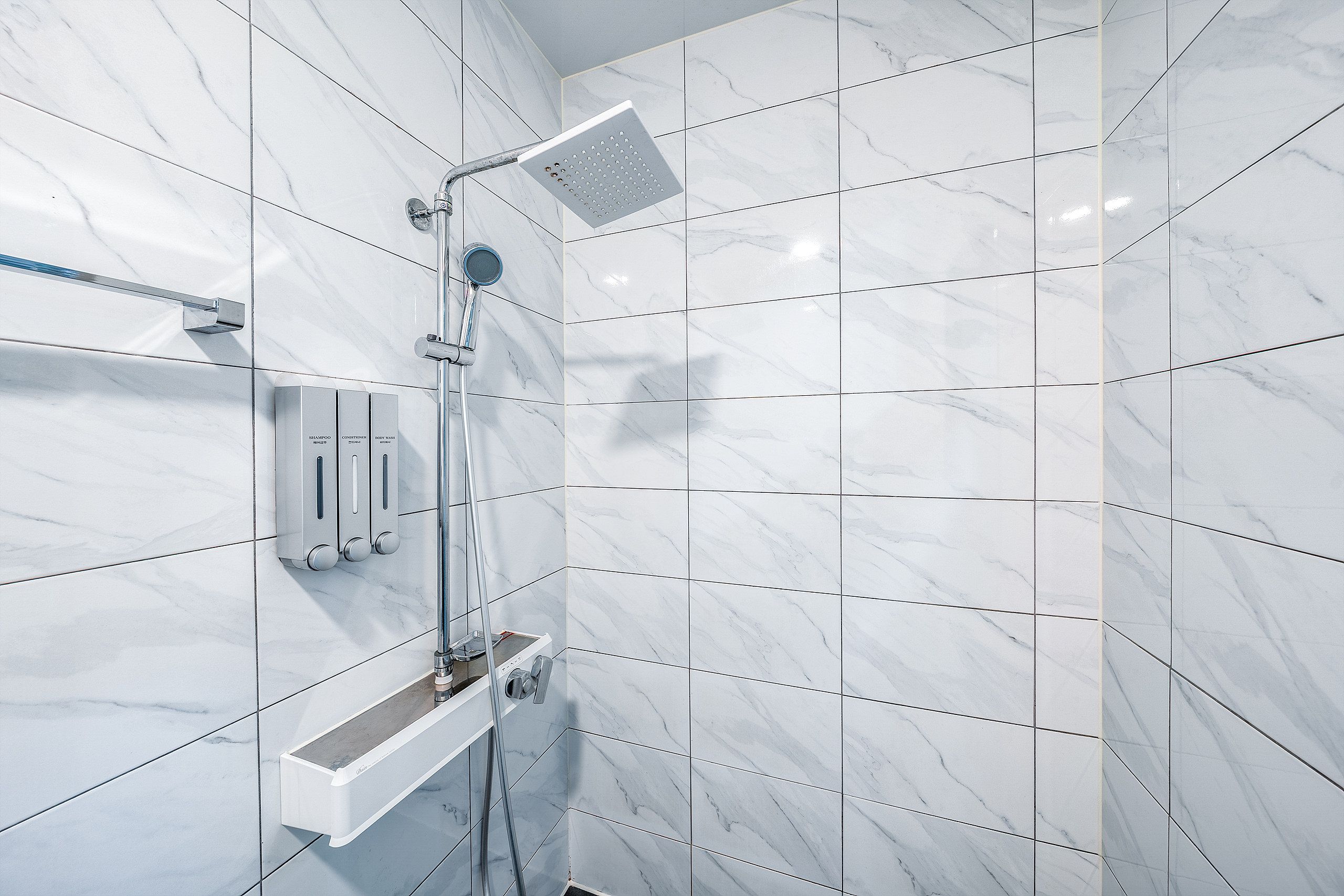 A modern bathroom with a shower, a vanity with a mirror, and a shelf with toiletries.