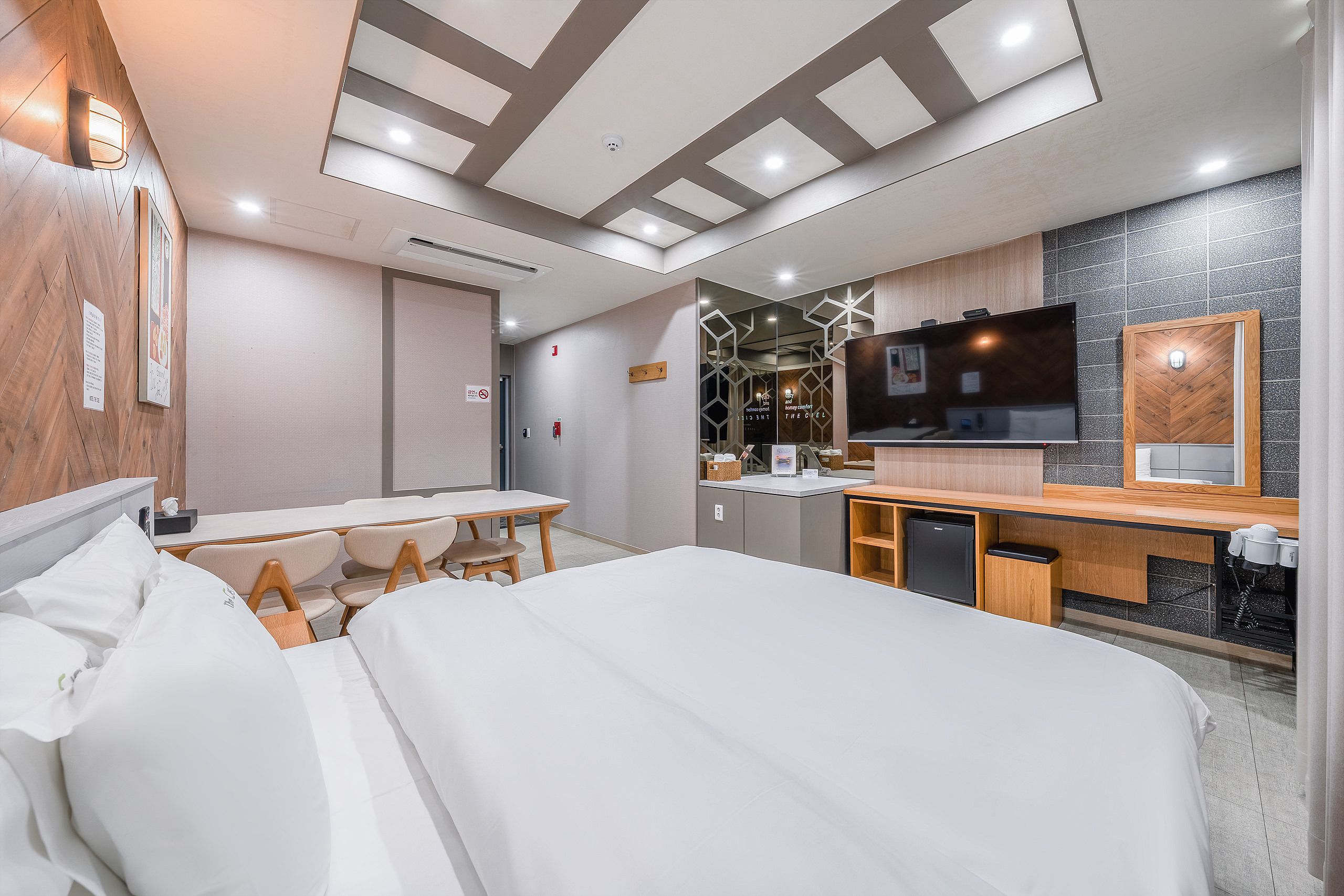 A hotel room with a bed, a desk, a television, and a bathroom.