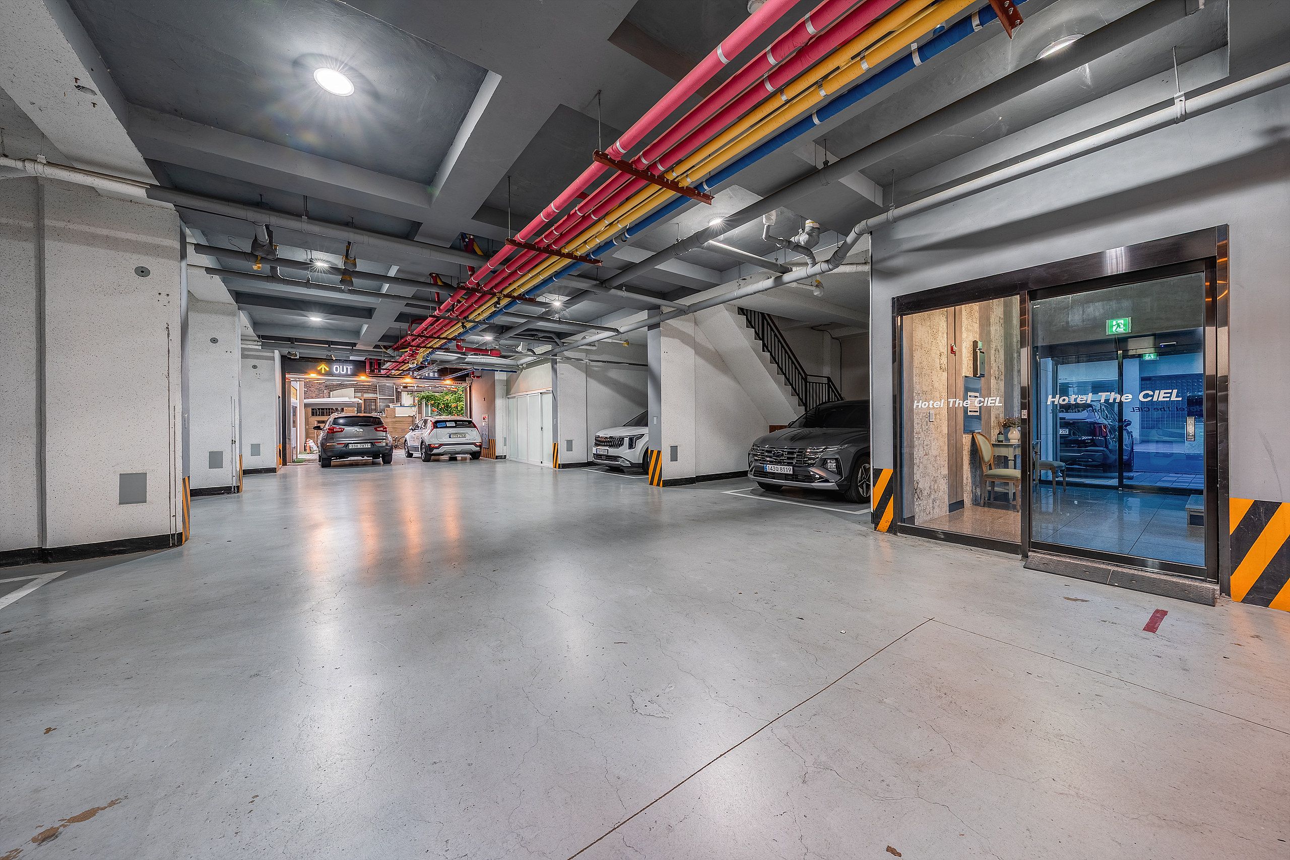 A multi-level parking garage with cars parked on different levels, visible staircases, and an exit sign.