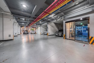 A multi-level parking garage with cars parked on different levels, visible staircases, and an exit sign.