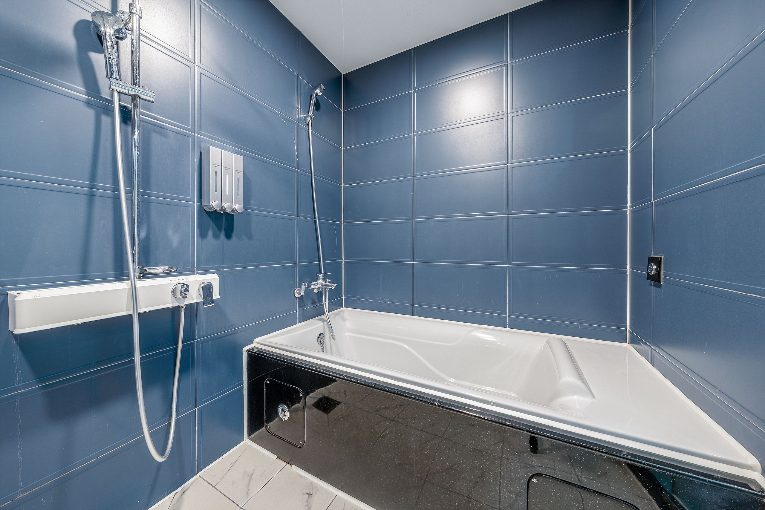 A modern bathroom with a bathtub, a shower area, and a hand dryer.