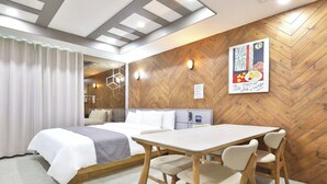 A hotel room with a bed, a table with chairs, a wooden herringbone wall, and a poster on the wall.