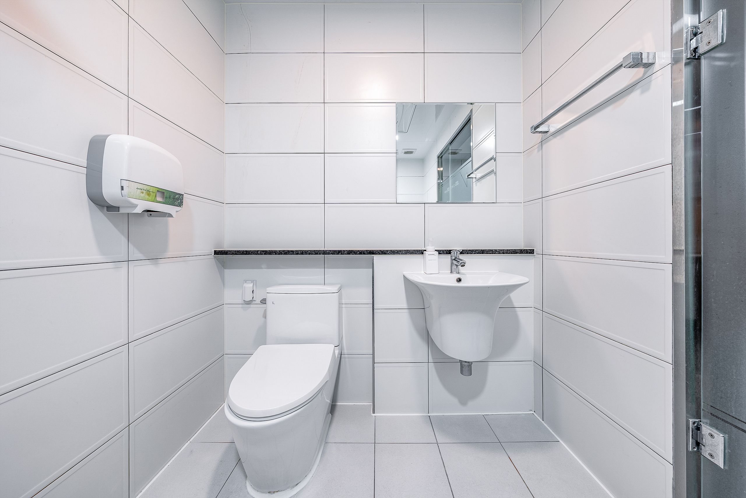 A modern bathroom with a toilet, sink, and hand dryer.