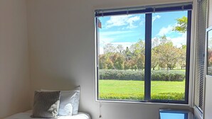 A bedroom with a bed, a window with a view of a garden and trees. - Lime Tree Lodge (Wānaka)