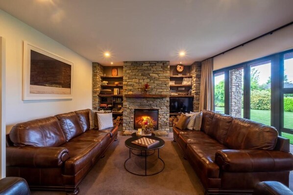 A living room with two leather sofas, a stone fireplace, and a television. - Lime Tree Lodge (Wānaka)