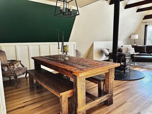 Une table à manger rustique en bois, accompagnée d’un banc, d’un luminaire suspendu et d’une lampe de style vintage.