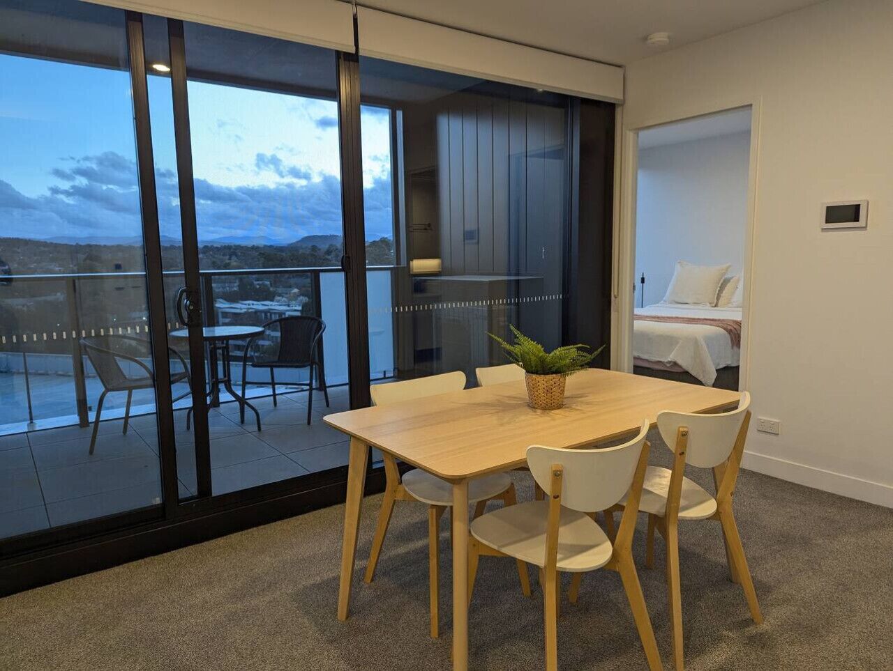 Ein modernes Zimmer mit einer großen Schiebeglastür, die auf einen Balkon mit Sitzgelegenheit führt.