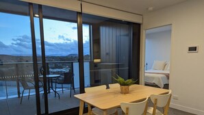 Une chambre moderne dotée d’une grande porte-fenêtre coulissante donnant sur un balcon aménagé avec des sièges d’extérieur.
