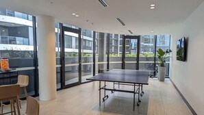 Un salón de conferencias moderno con una gran mesa, sillas y amplias ventanas que ofrecen vistas a la ciudad.