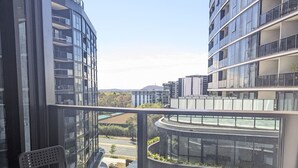 Un apartamento moderno con balcón, ventanas amplias y vista a una calle y zonas verdes.
