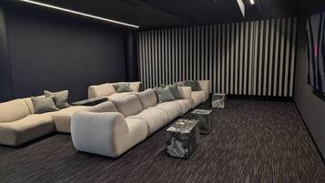 Ein moderner Heimkino-Raum mit einer Eckcouch, einem kleinen Couchtisch und einer gestreiften Wand.