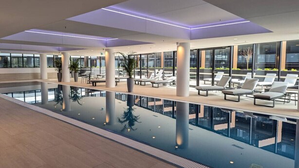 Une piscine intérieure moderne, dotée de chaises longues et de plantes en pot.