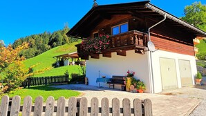 Een chalet met een houten balkon, een overdekte patio en een omheinde tuin.