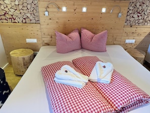 A hotel room with a wooden headboard, checkered bedding, and a bedside table with a lamp. - Almchalet Zillertal by Interhome (Aschau im Zillertal)