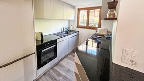 Una cuina moderna amb armaris blancs, taulell negre i forn integrat.
