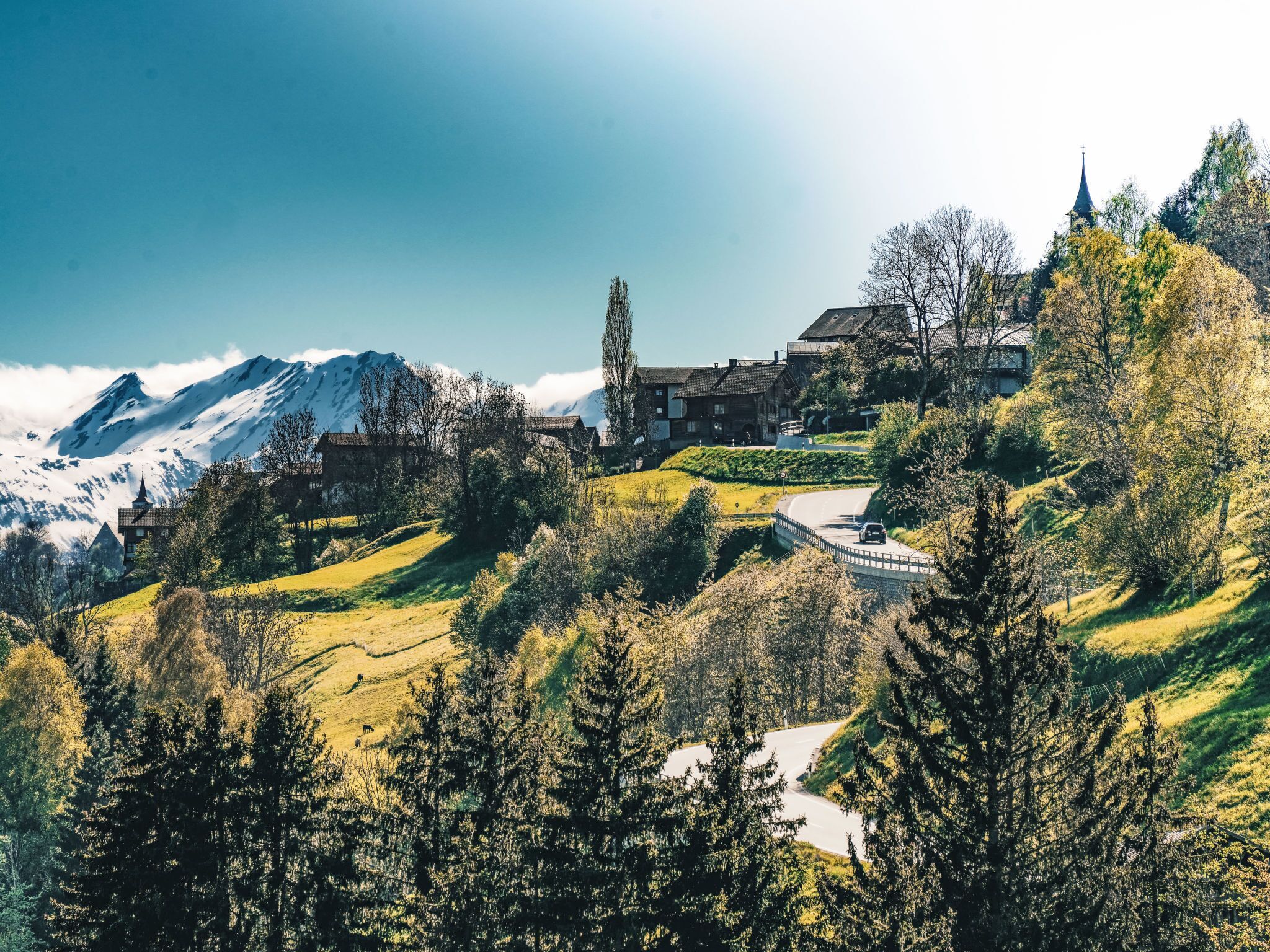 Eine gebirgige Landschaft mit einem Gebäude, das mehrere Fenster und einen markanten Turm besitzt.