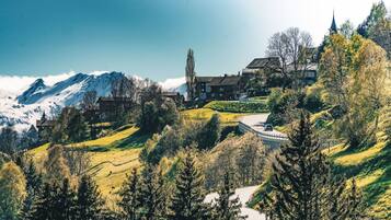 Eine gebirgige Landschaft mit einem Gebäude, das mehrere Fenster und einen markanten Turm besitzt.