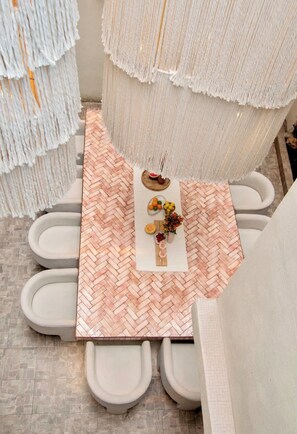 Een badkamer met een visgraatvloer, een wit wastafelmeubel, twee toiletten en een decoratieve wandversiering.