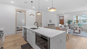 Een moderne keuken met een centraal eiland, een inbouwoven en hanglampen.