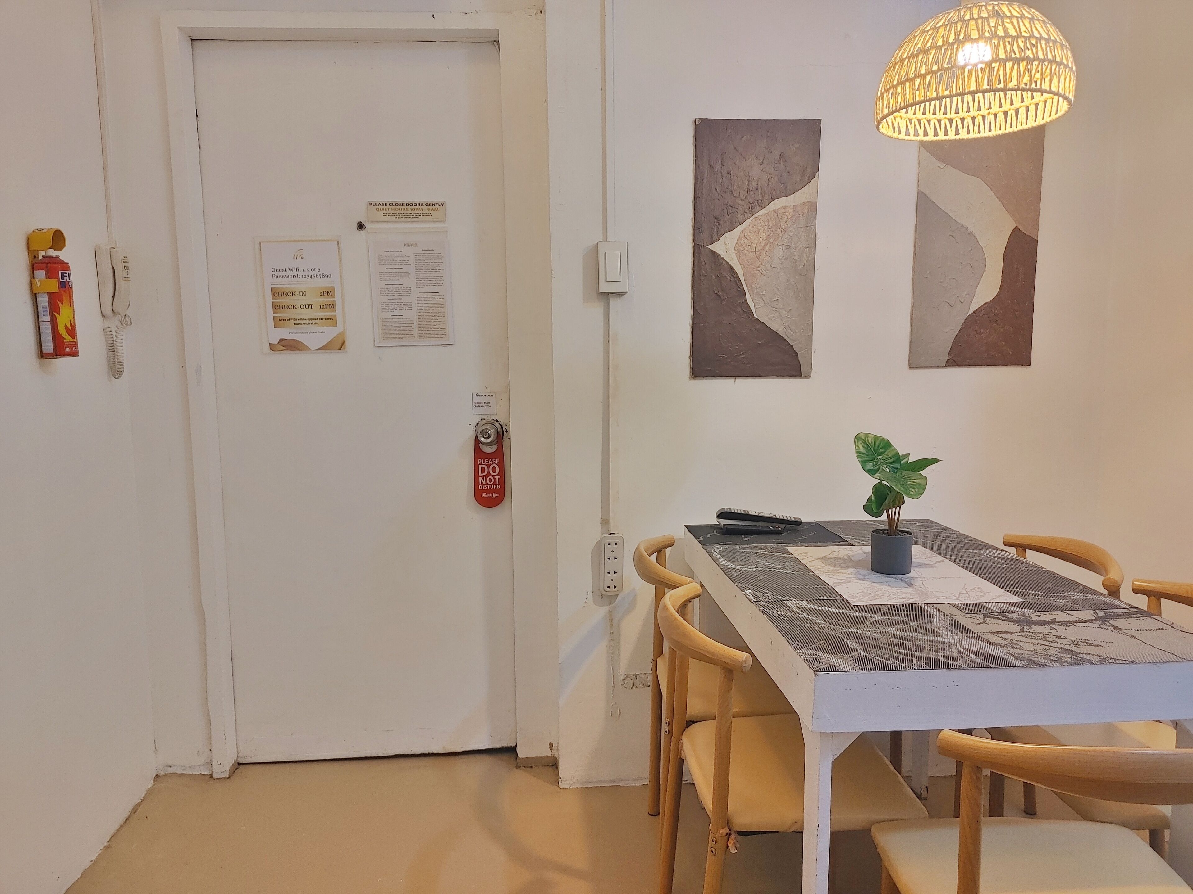 A dining area with a white table, wooden chairs, a potted plant, and abstract wall art.